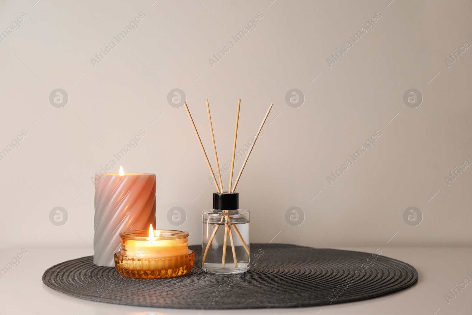 Photo of Aromatic reed air freshener and burning candles on white table