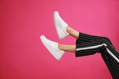 Woman in stylish sport shoes on pink background