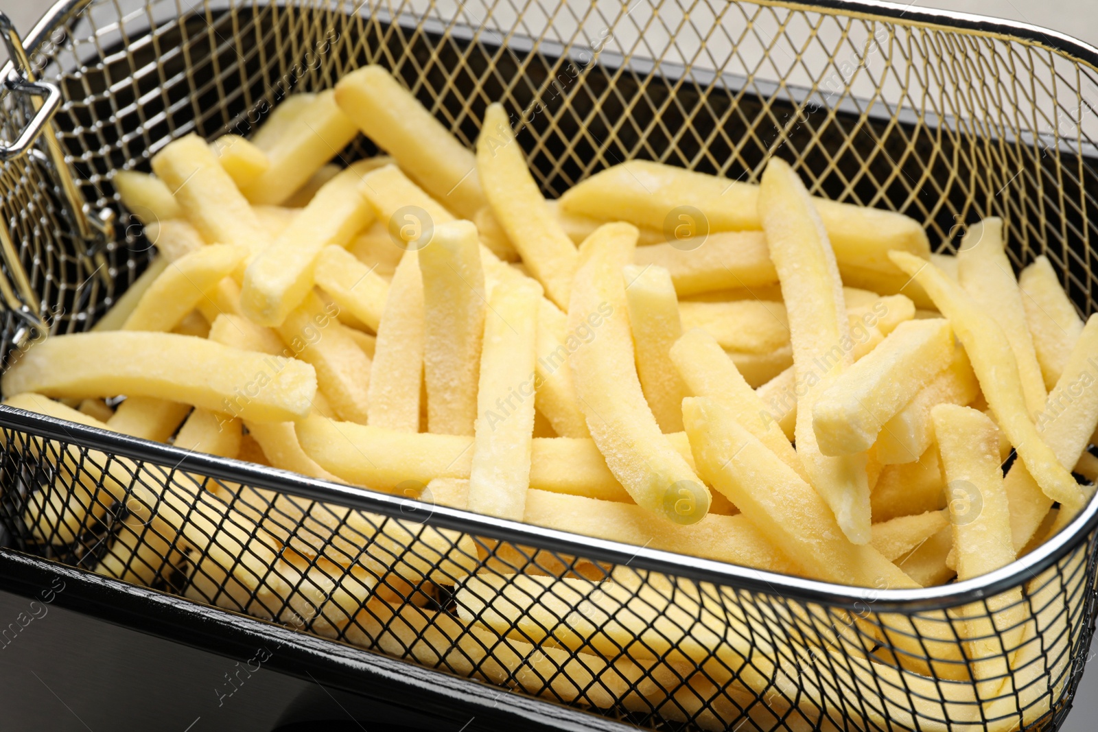 Photo of Uncooked french fries in metal basket, closeup