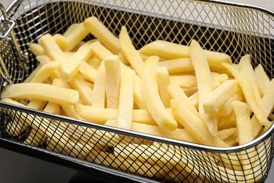 Uncooked french fries in metal basket, closeup