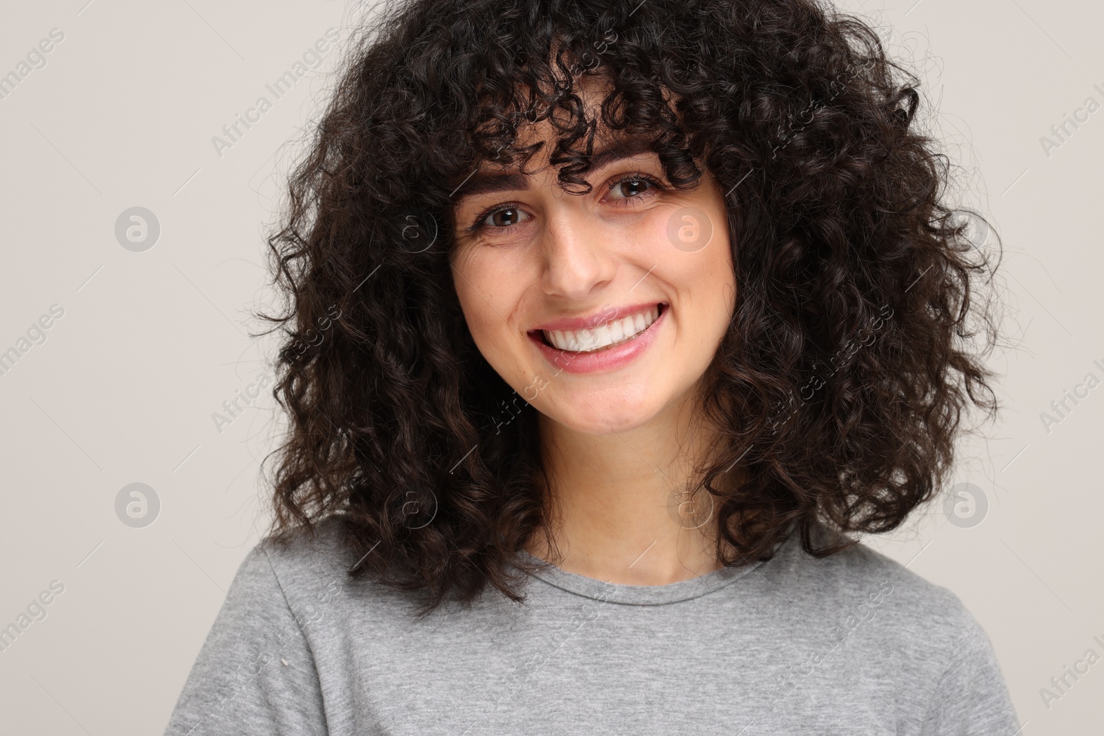 Photo of Young woman using teeth whitening strip on light grey background