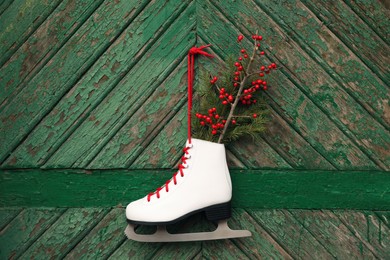 Ice skate with Christmas decor hanging on green wooden wall