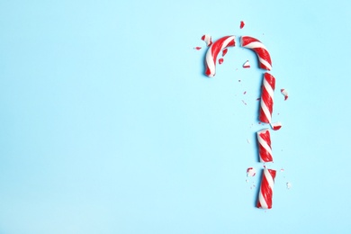Photo of Broken candy cane and space for text on color background, top view
