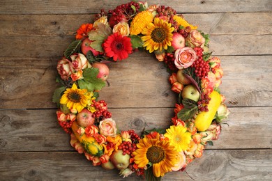 Beautiful autumnal wreath with flowers, berries and fruits on wooden background, top view. Space for text