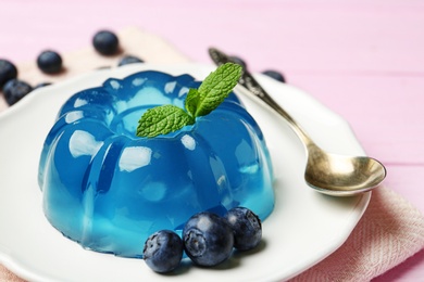 Photo of Plate of delicious blue jelly with berries on pink wooden background