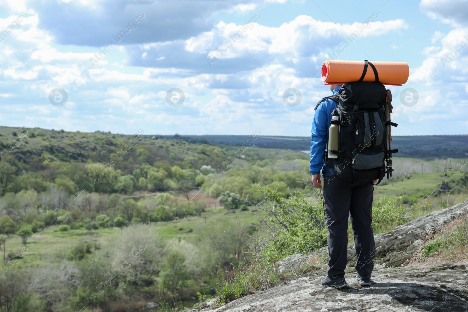 Photo of Hiker with backpack ready for journey on rocky hill, back view