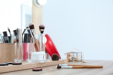 Photo of Organizer with cosmetic products for makeup on table near mirror. Space for text