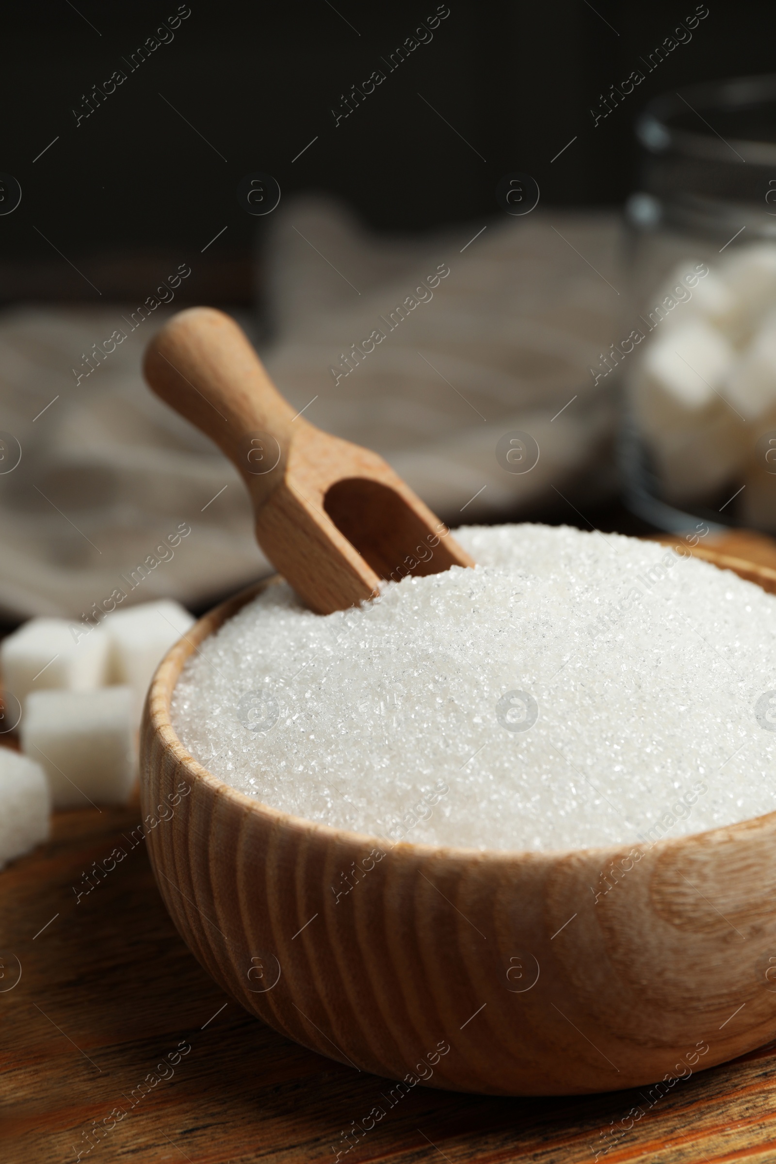 Photo of Granulated sugar in bowl on wooden table