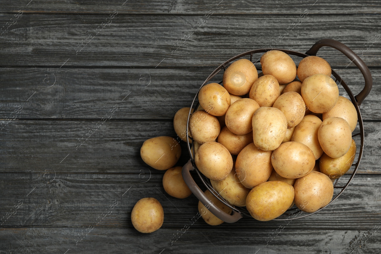 Photo of Raw fresh organic potatoes on black wooden background, top view. Space for text