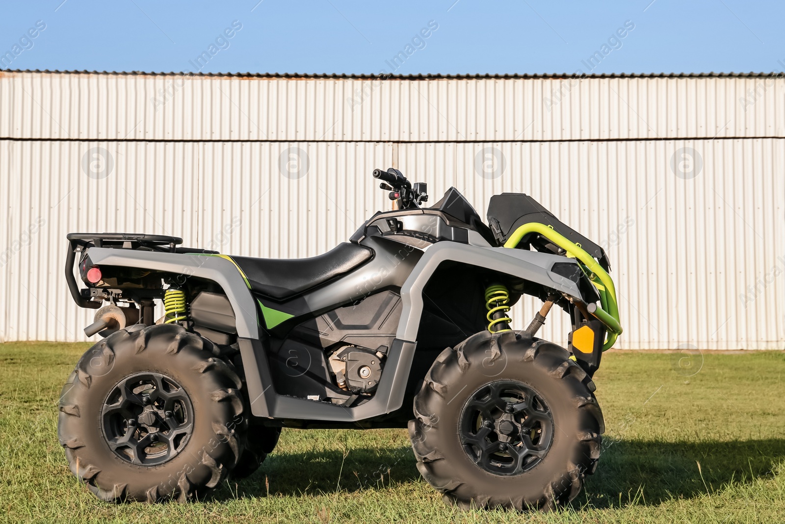 Photo of Modern quad bike in field near hangar on sunny day