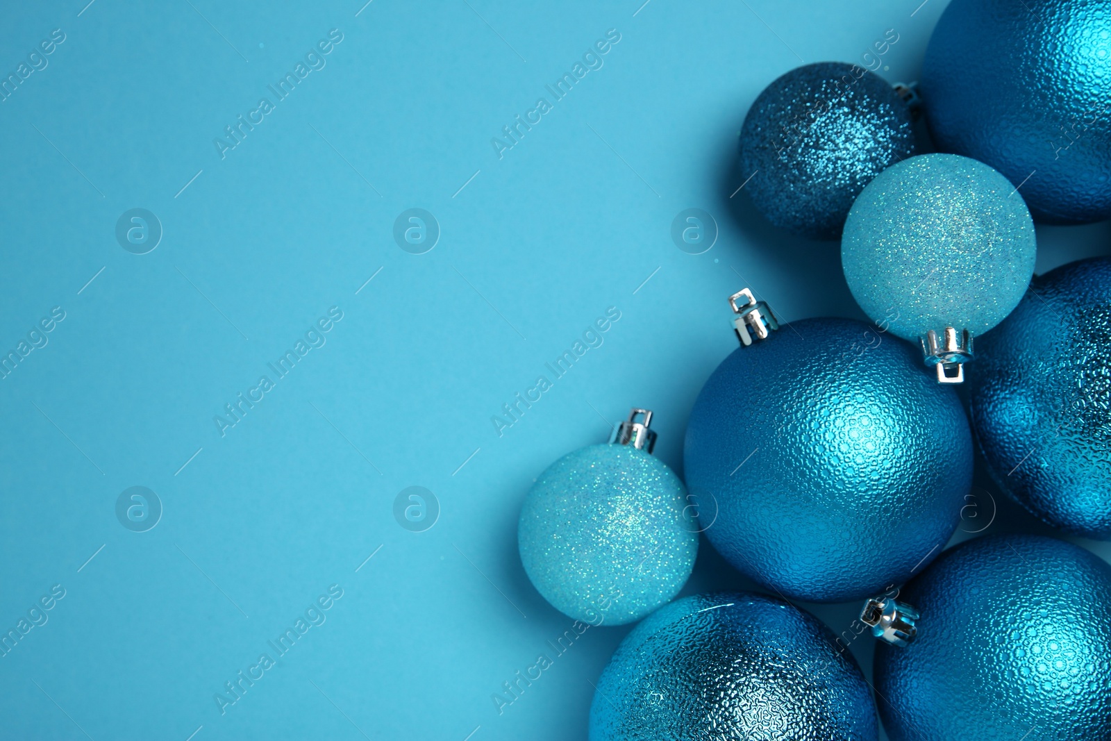 Photo of Christmas balls on light blue background, top view. Space for text