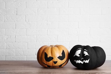 Photo of Pumpkins with scary faces near brick wall, space for text. Halloween decor