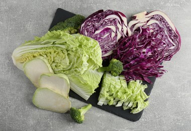 Photo of Different types of cut cabbage on light grey table, flat lay