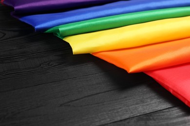 Rainbow LGBT flag on black wooden background, closeup. Space for text