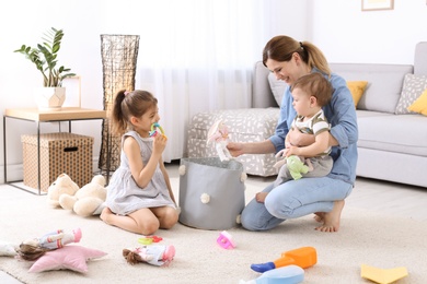 Housewife and children picking up toys after playing at home