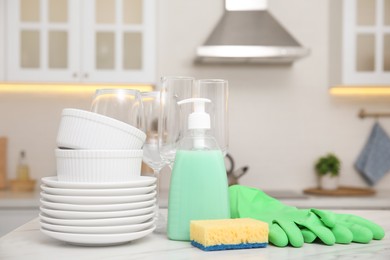 Photo of Set of clean dishes and cleaning product on table in stylish kitchen