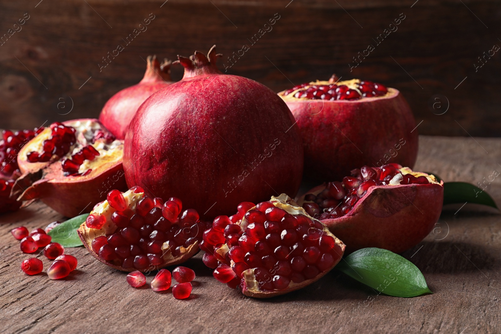 Photo of Composition with ripe pomegranates and leaves on table