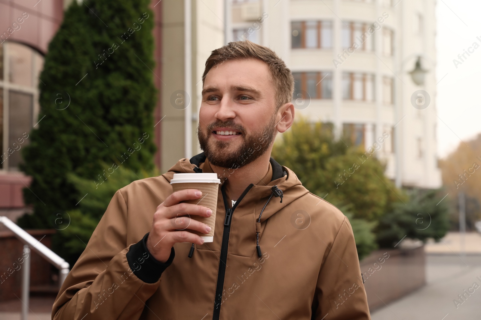 Photo of Handsome man wearing stylish clothes with cup of coffee on city street. Autumn walk
