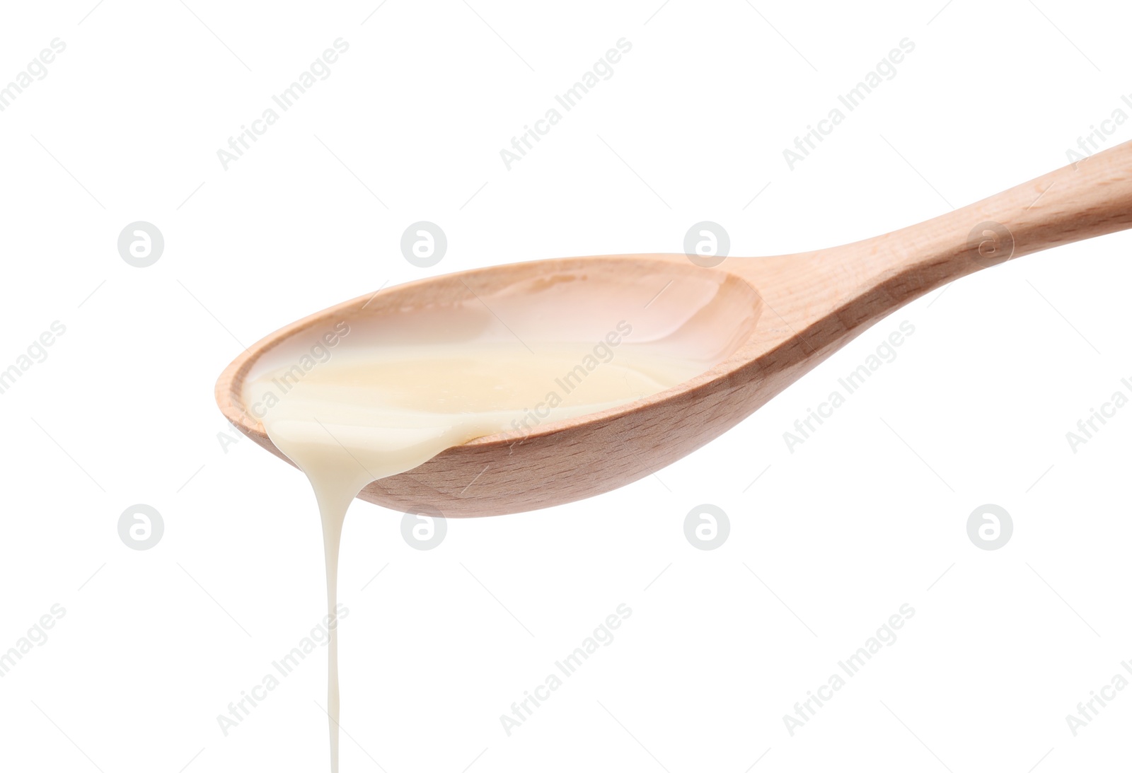 Photo of Pouring condensed milk from wooden spoon isolated on white