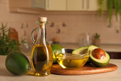 Photo of Fresh avocados and cooking oil on beige marble table in kitchen
