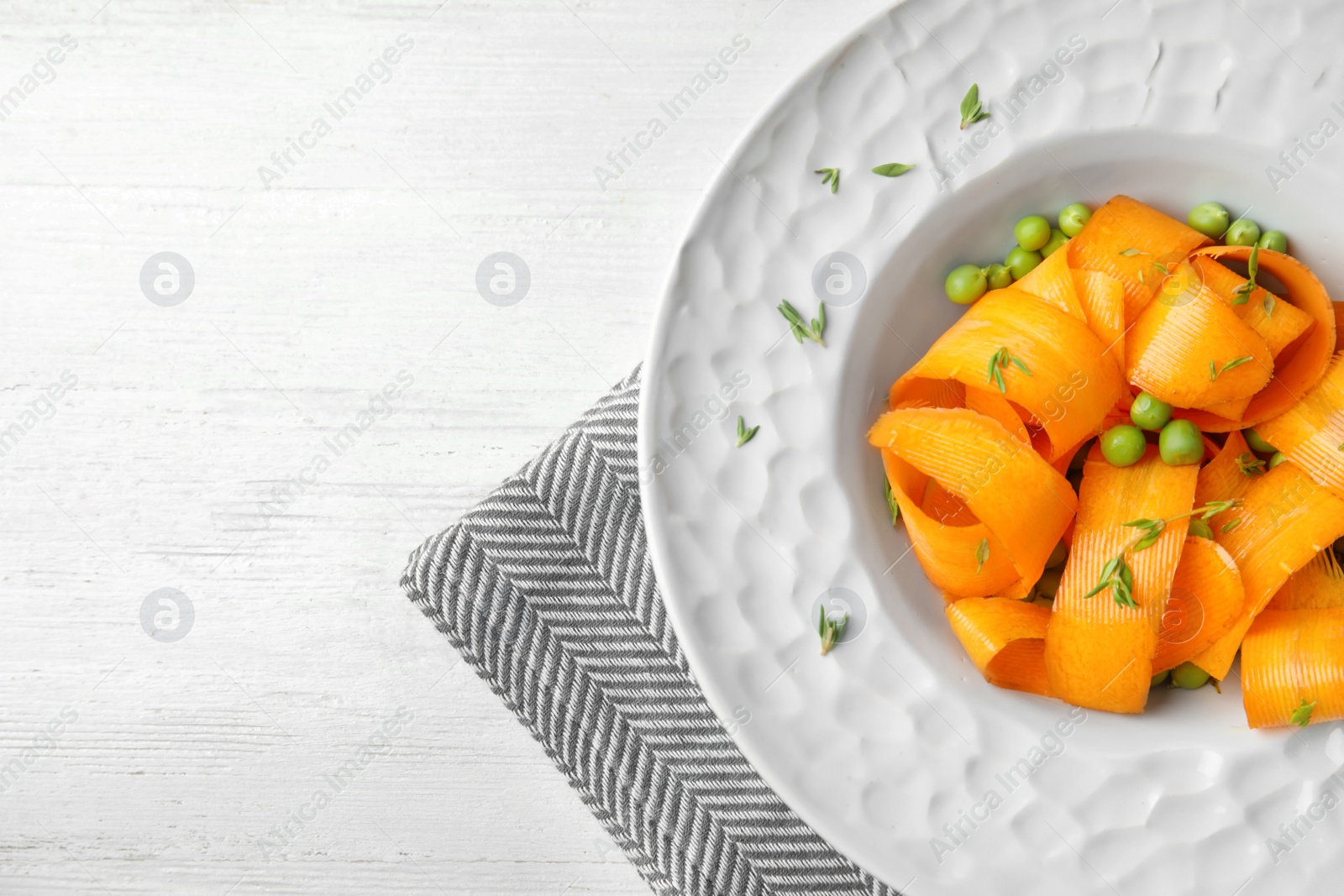 Photo of Tasty salad with fresh carrot in plate on table, top view