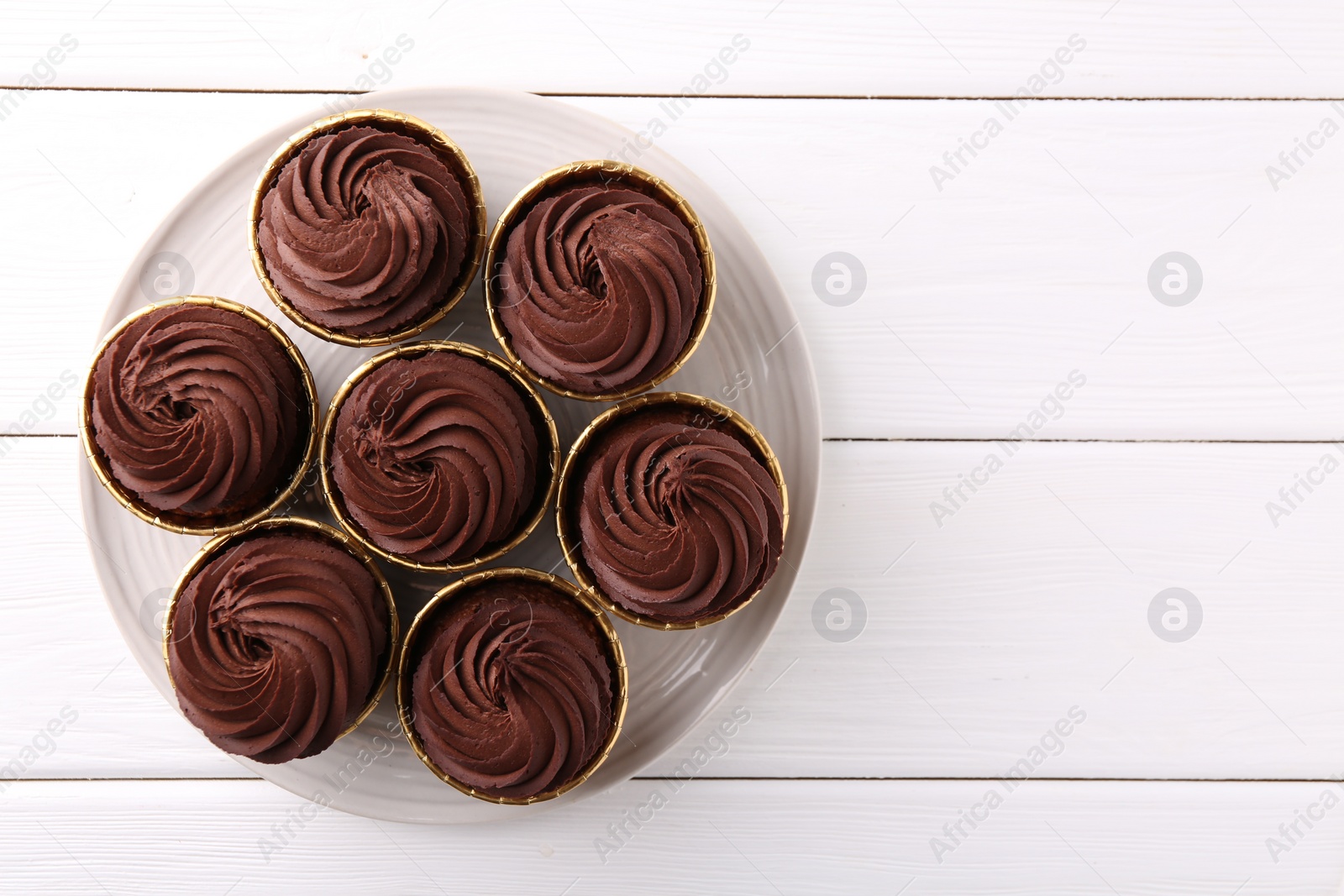 Photo of Delicious chocolate cupcake on white wooden table, top view. Space for text