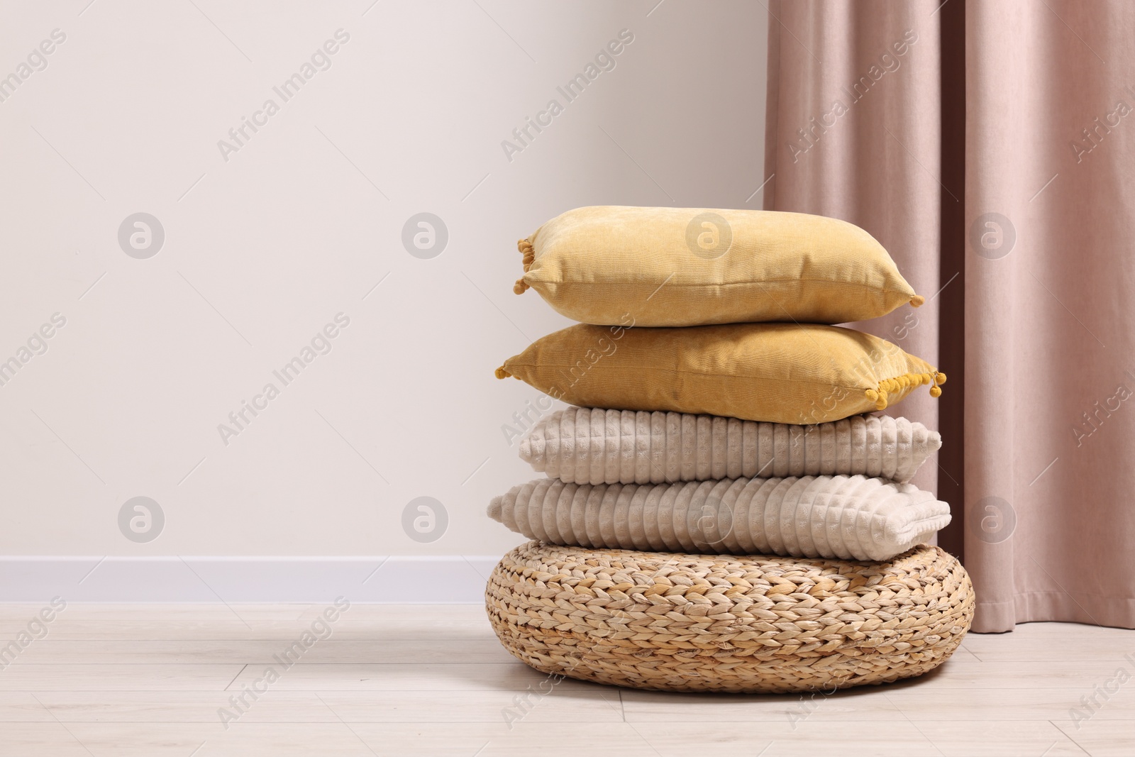 Photo of Soft pillows on wicker pouf in room, space for text