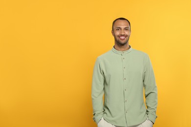 Portrait of handsome young man on orange background, space for text
