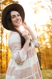 Photo of Beautiful woman wearing hat in sunny park. Autumn walk