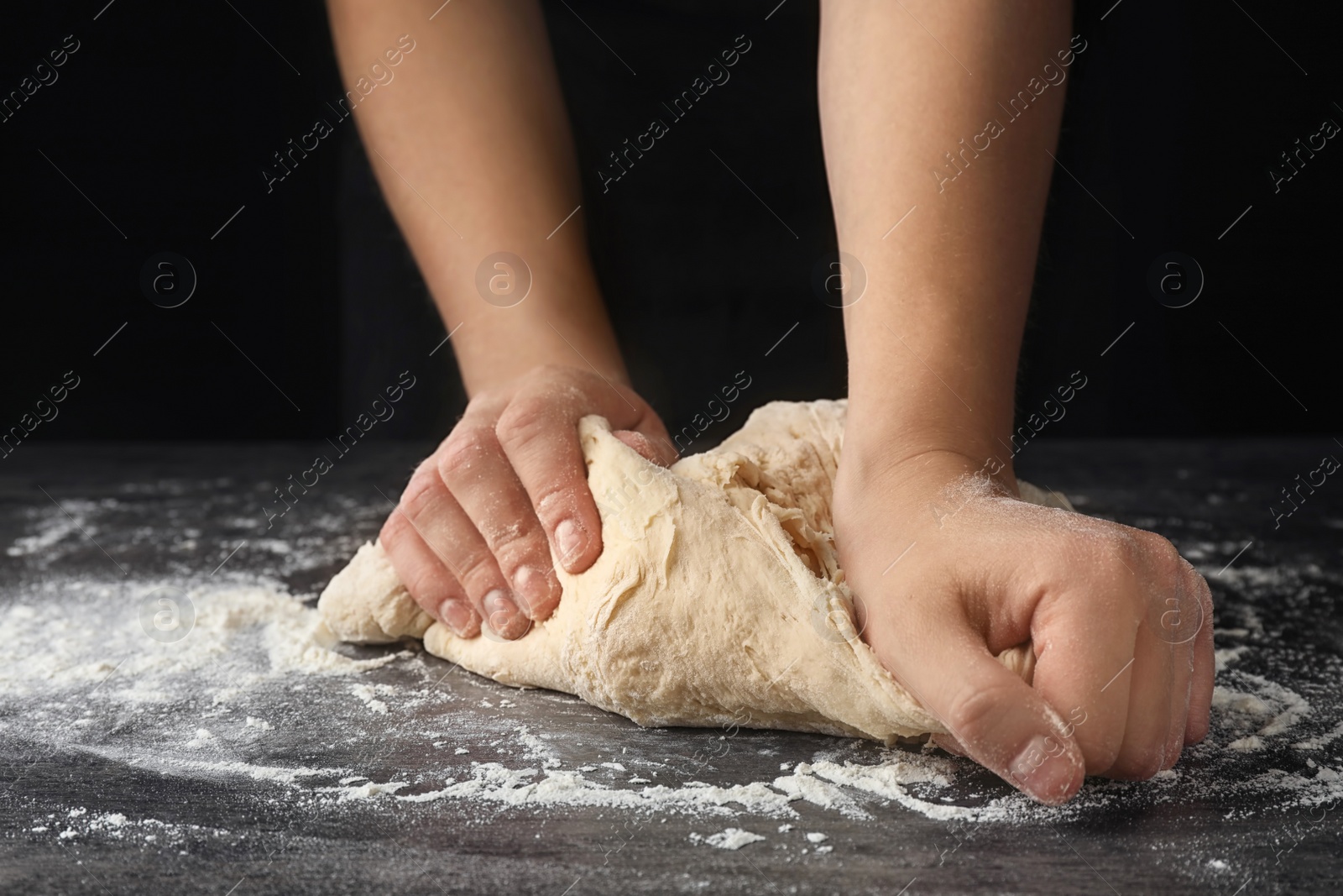 Photo of Young woman kneading dough at table, closeup