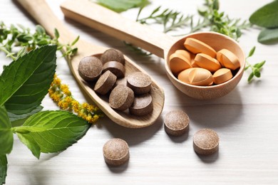 Photo of Different pills, herbs and flowers on white wooden table, closeup. Dietary supplements