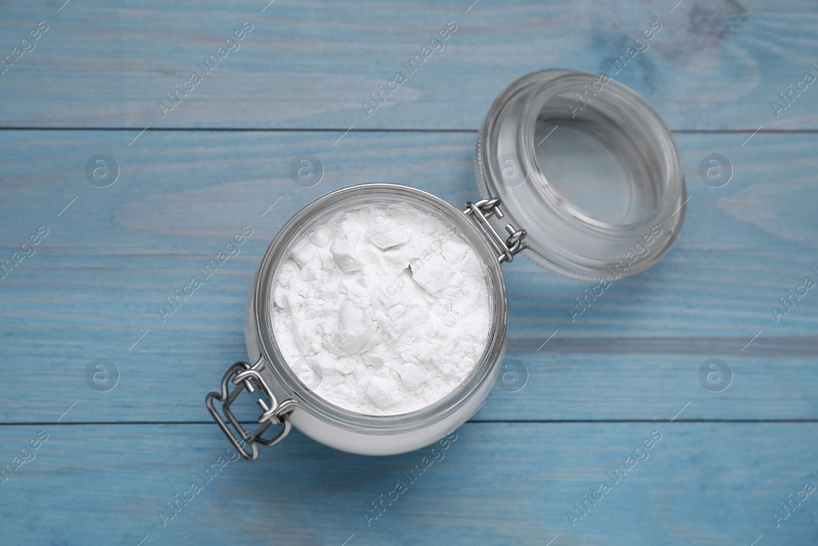 Photo of Glass jar of natural starch on light blue wooden table, top view