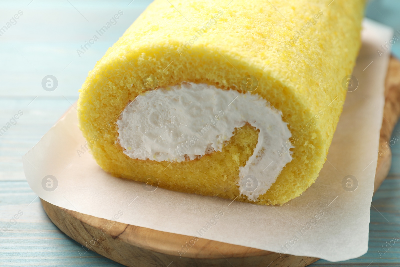 Photo of Delicious cake roll on light blue wooden table, closeup