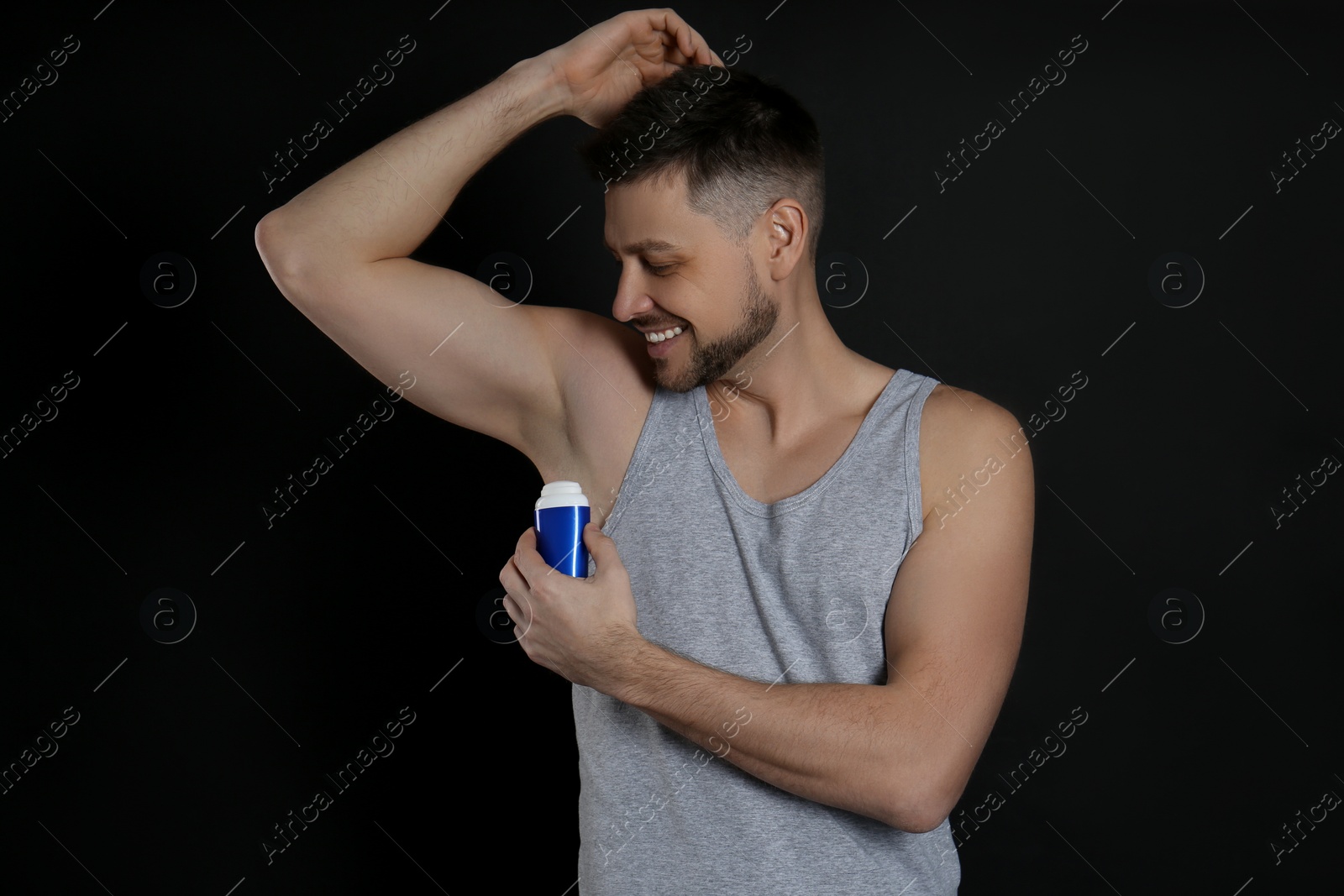 Photo of Handsome man applying deodorant on black background