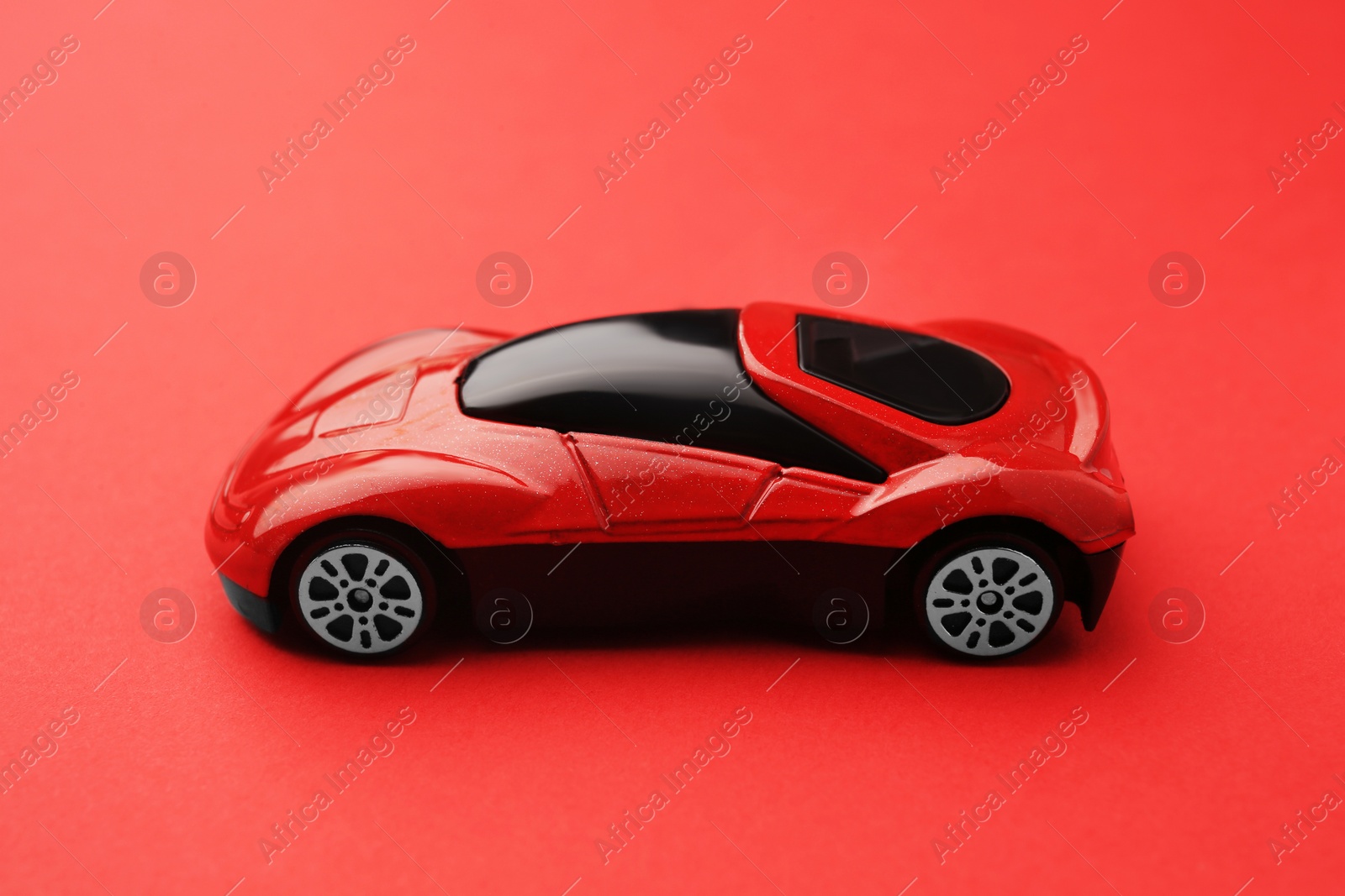 Photo of One bright car on red background. Children`s toy