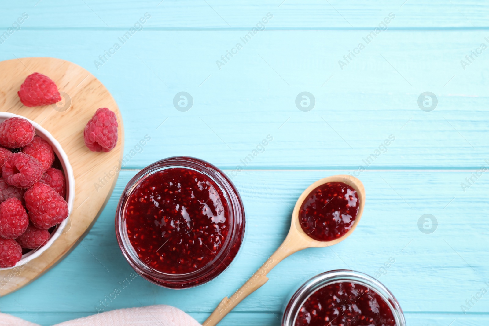 Photo of Flat lay composition with delicious raspberry jam on light blue wooden table. Space for text