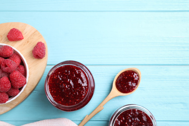 Flat lay composition with delicious raspberry jam on light blue wooden table. Space for text