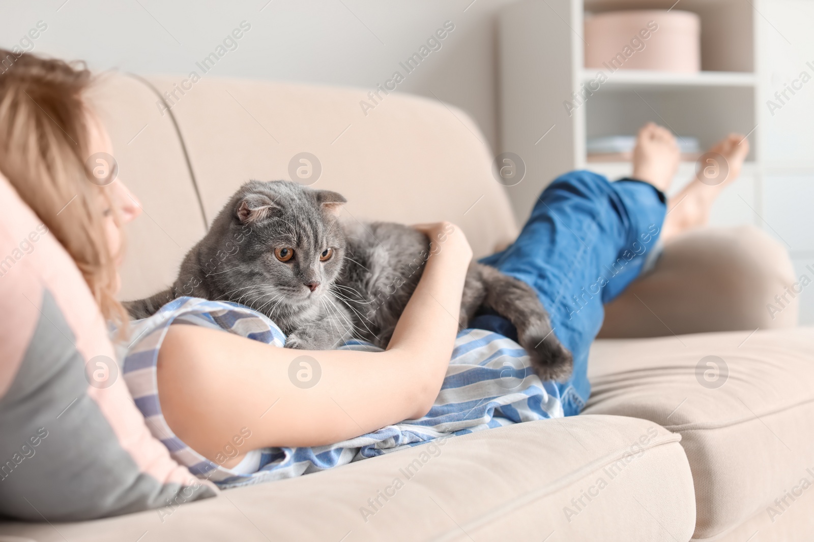 Photo of Young woman with her cute pet cat on sofa at home