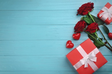 Photo of Gift boxes, roses and red hearts on turquoise wooden background, flat lay with space for text. Valentine's Day celebration