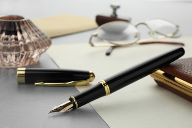 Photo of Stylish fountain pen and cap on grey textured table, closeup