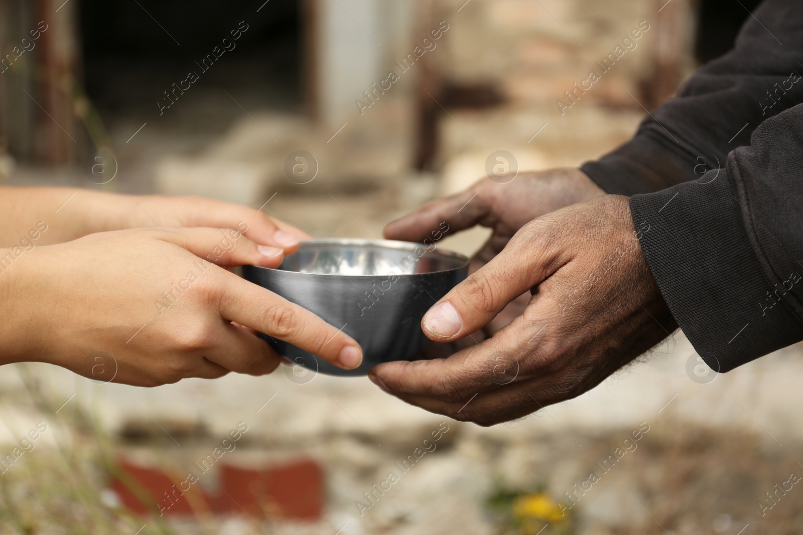 Photo of Woman giving poor homeless man bowl of wheat outdoors, closeup