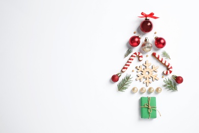 Photo of Christmas tree silhouette of fir branches and festive decoration on white background, top view