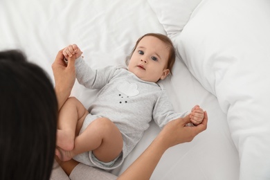Photo of Cute baby playing with mother on bed, above view