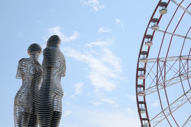 BATUMI, GEORGIA - JUNE 14, 2022: Movable sculptural composition Ali and Nino near Ferris wheel, low angle view