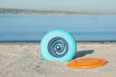 Photo of Plastic frisbee discs on sandy beach near river