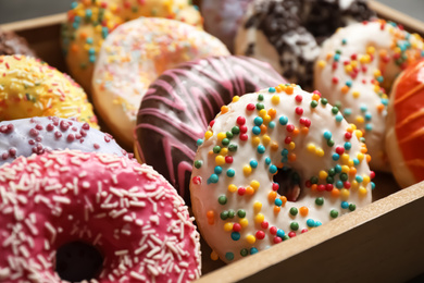 Photo of Yummy donuts with sprinkles in box, closeup