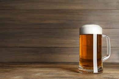 Photo of Mug of tasty beer on wooden table. Space for text