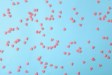Bright heart shaped sprinkles on light blue background, flat lay