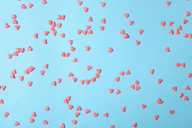 Photo of Bright heart shaped sprinkles on light blue background, flat lay