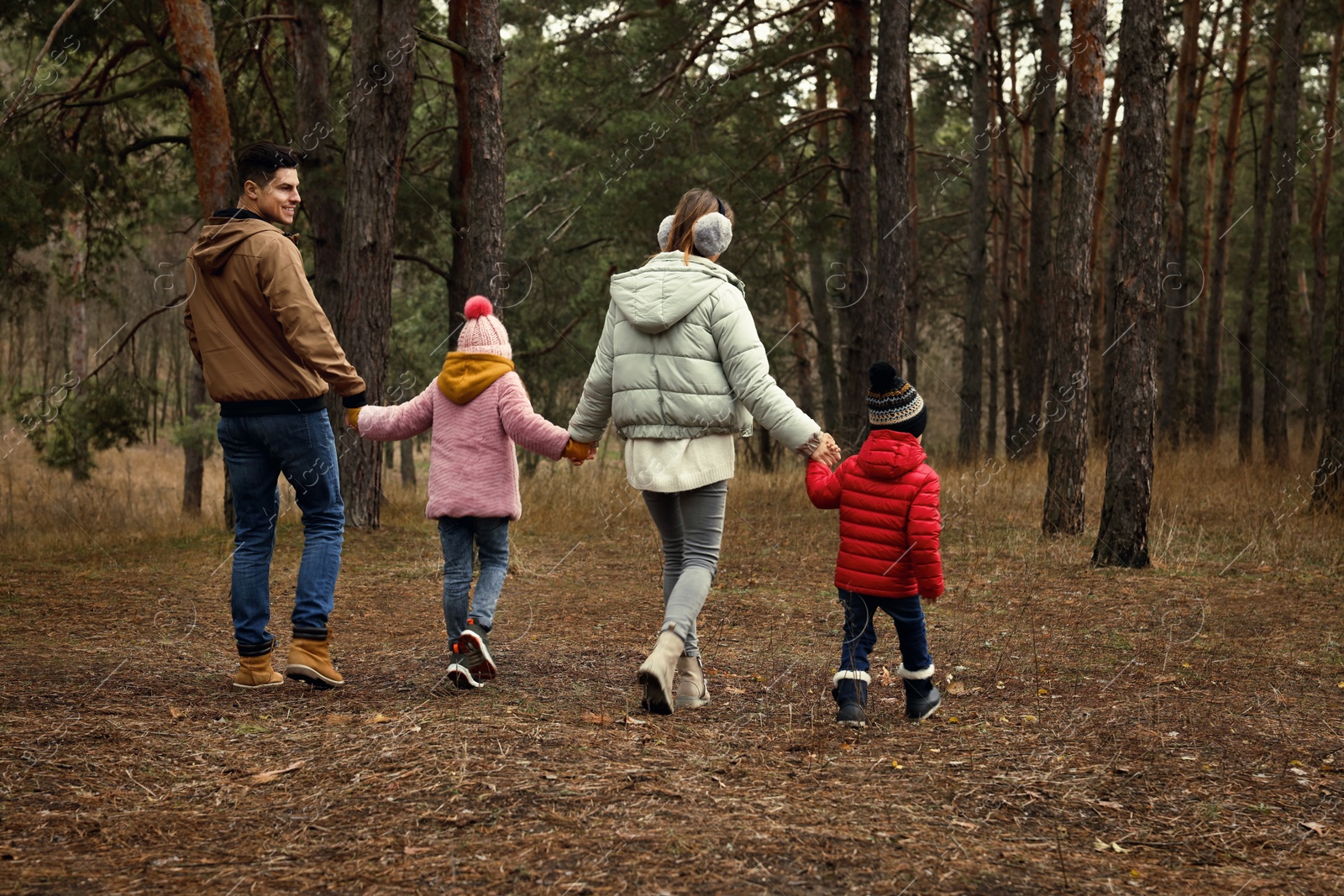 Photo of Happy family spending time together in forest, back view